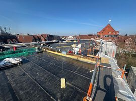 Bautenstand vom 18.03.2026: Die Arbeiten auf der Baustelle entwickeln sich weiterhin sehr positiv. Der Rohbau ist vollständig abgeschlossen, sodass das Gebäude mit eingebauten Fenstern und Haustüren bereits seine endgültige Form erkennen lässt. Damit ist ein wesentlicher Meilenstein in der Projektentwicklung erreicht. Auch im Bereich der Dacharbeiten wurden entscheidende Fortschritte erzielt: Sämtliche vorbereitenden Maßnahmen sind abgeschlossen, aktuell erfolgt die Abdichtung des Hauptdachs. Parallel dazu schreiten die technischen Ausbaugewerke zügig voran. Die Elektroinstallation sowie die Arbeiten in den Bereichen Heizung, Sanitär und Lüftung sind bereits weit fortgeschritten und werden planmäßig in den oberen Geschossen fortgeführt. Im Innenausbau zeigt sich ebenfalls ein hoher Fertigstellungsgrad. Die Trockenbauarbeiten sind größtenteils umgesetzt, erste Bereiche bereits geschlossen. Die Dämmarbeiten im Keller stehen kurz vor dem Abschluss, und die Stahlzargen für die Innentüren wurden erfolgreich eingebaut. Darüber hinaus sind die Estricharbeiten im Kellergeschoss abgeschlossen und werden derzeit im Erdgeschoss fortgeführt. Zeitgleich haben die Fassadenarbeiten begonnen, wodurch das Gebäude auch äußerlich zunehmend Gestalt annimmt. Insgesamt verläuft die Umsetzung des Projekts planmäßig und entspricht unseren hohen Qualitätsansprüchen.